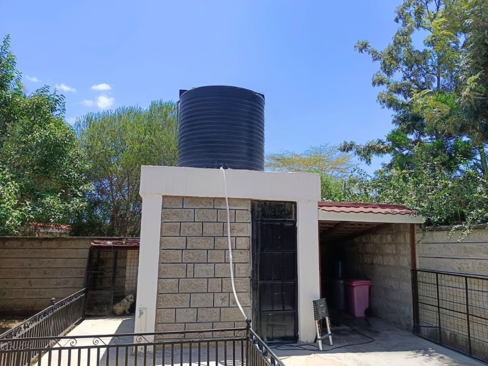 Black plastic water tank on elevated stand in Kenyan home, ideal for residential water storage