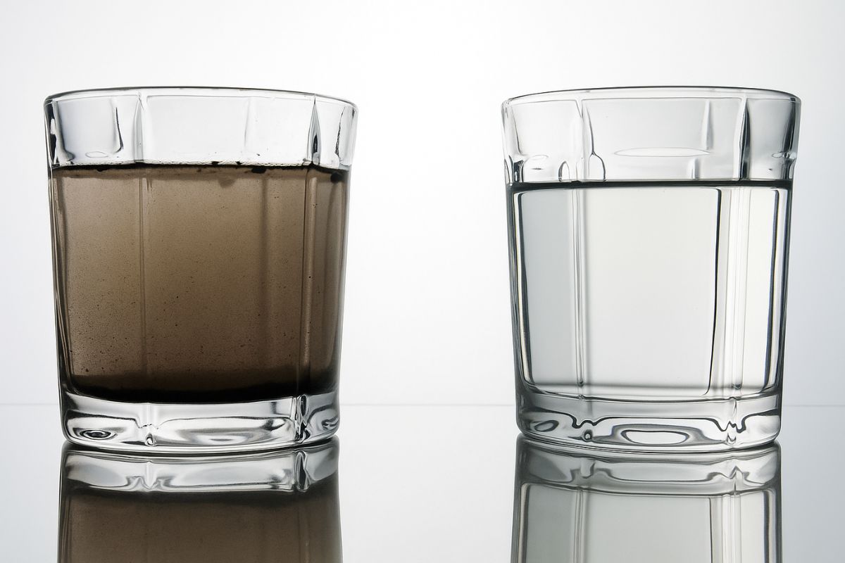 A glass of dirty water next to a glass of clean water, illustrating the result of emergency water tank cleaning.