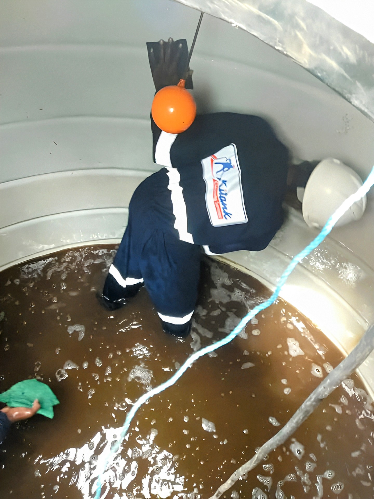 A KiTank professional inside a dirty water tank performing an emergency water tank cleaning service in Kenya